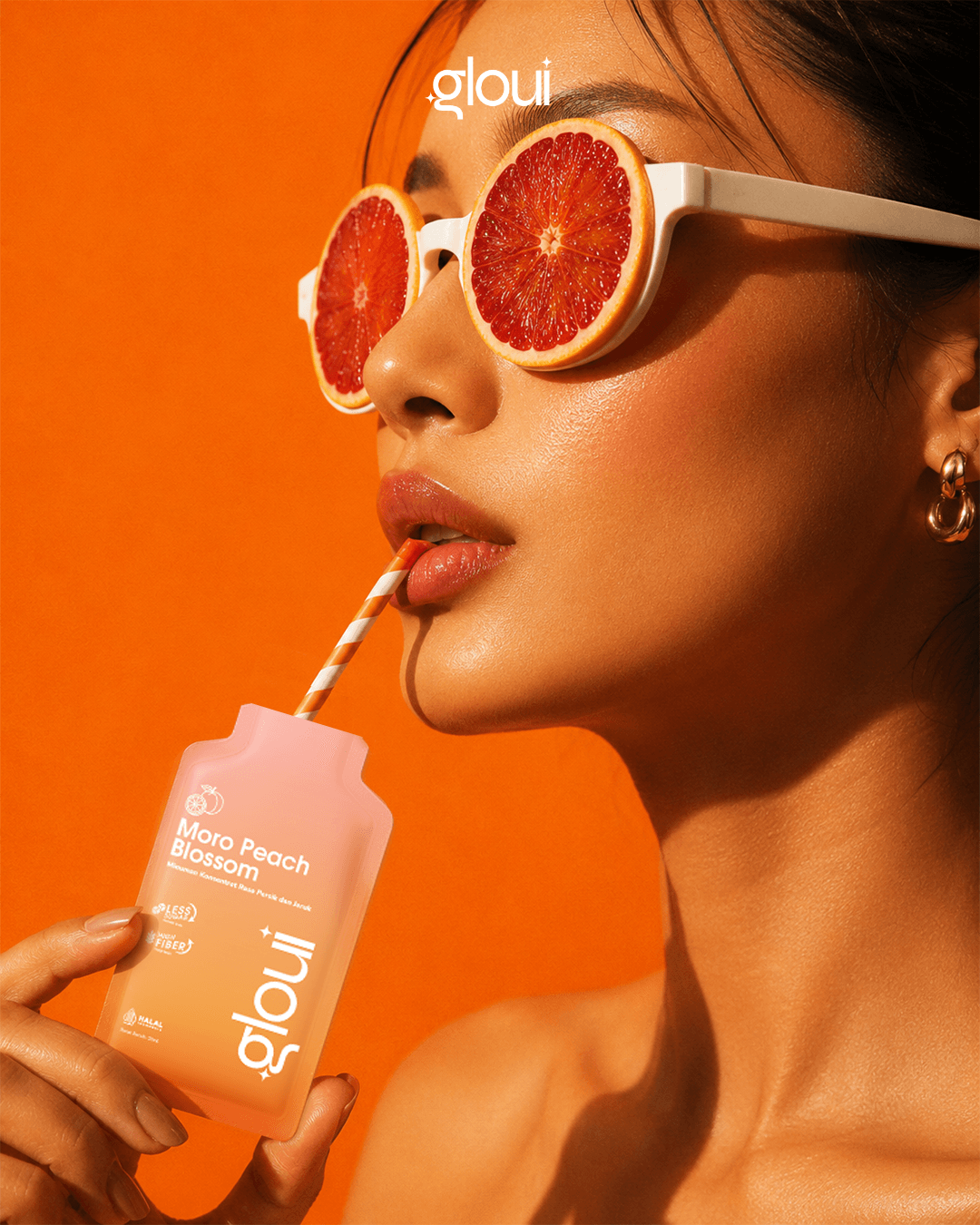 Woman in blood-orange sunglasses sipping a Gloui Moro Peach Blossom shot
